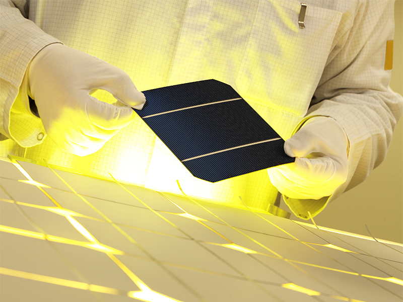 a tech worker holds a piece of a solar panel