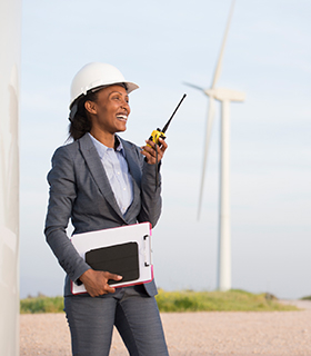 Image of woman using a walkie-talkie in front of a windmill.